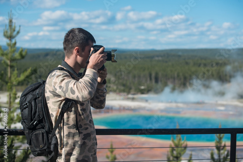 Tourist man taking photos and enjoy the view of geysers in Yellowstone National Park
