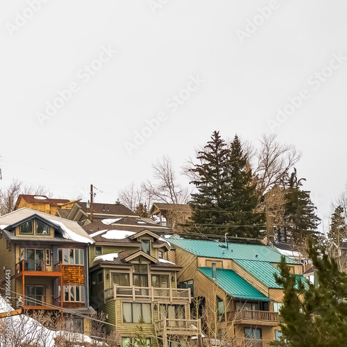 Square frame Hill homes with balconies and snowy roofs against cloudy sky in winter © Jason