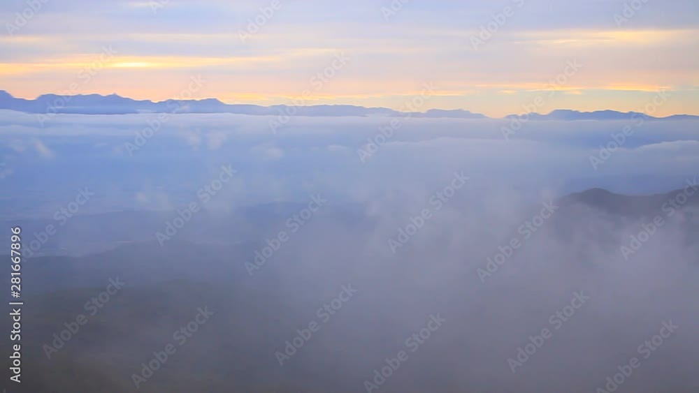 Panning wide shot of mountains in clouds at sunset Panning wide shot of mountains in clouds at sunset