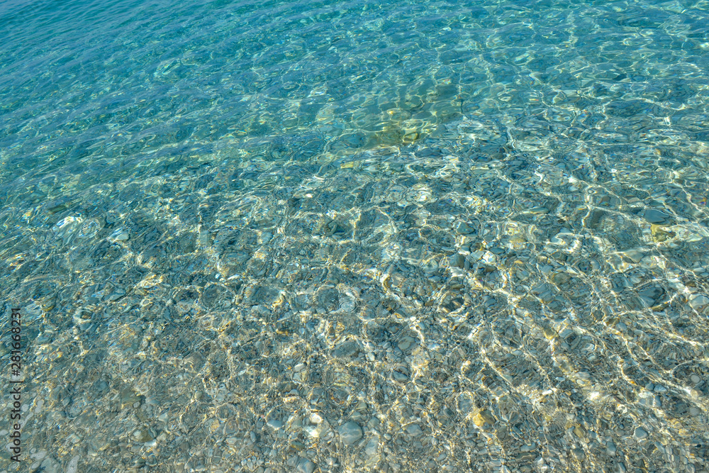 Beautiful colorful pebbles and big stone under turquoise blue clear water, scenic marine background or texture, top view