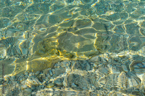 Beautiful colorful pebbles and big stone under turquoise blue clear water  scenic marine background or texture  top view