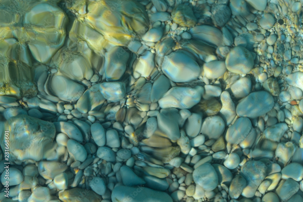 Beautiful colorful pebbles and big stone under turquoise blue clear water, scenic marine background or texture, top view Beautiful colorful pebbles and big stone under turquoise blue clear water, scenic marine background or texture, top view