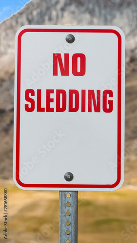 Vertical frame Close up of a No Sledding sign with a towering mountain in the background