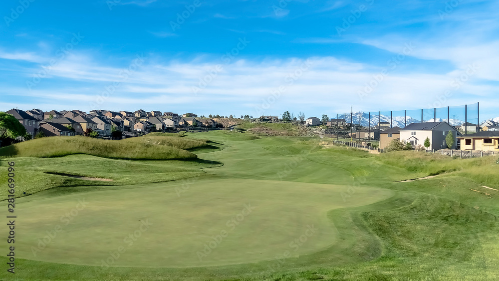 Panorama Golf course with view of lovely homes and mountain under blue sky with clouds