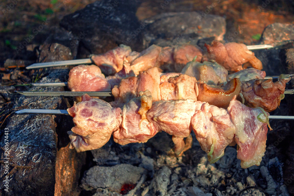 Shish kebab on skewers is fried on a brazier made of stones in the forest.