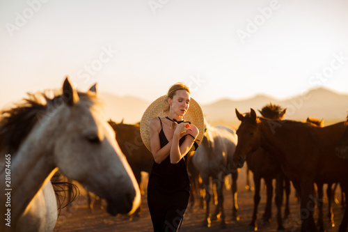 Woman in a black dress among wild horses in Turkey