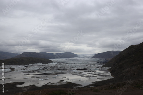 front view of a glacier and lake under a cloudy sky 