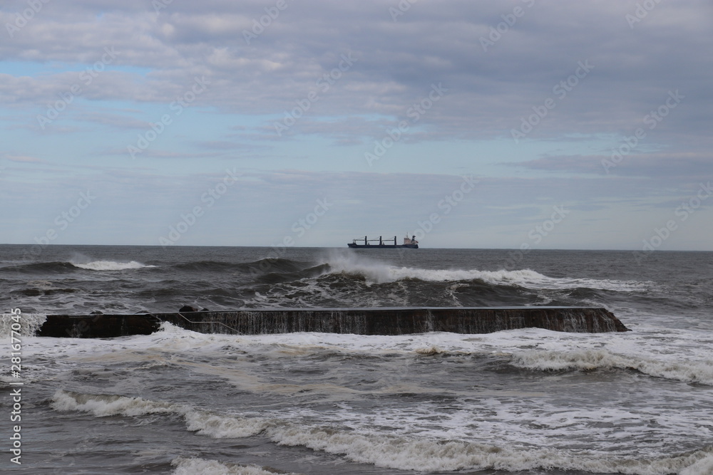 small waves breaking over a breakwater with container ship 