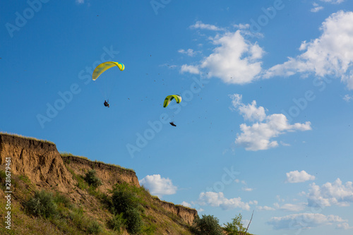 paraglider flying in the blue sky among the white clouds. Paragliding