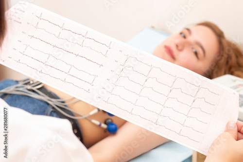 The doctor cardiologist looks at the printout of the cardiogram of patients, which lies on the couch. patient girl on a cardiogram procedure.
