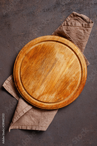 Fotografi Brown table with empty pizza board and linen napkin