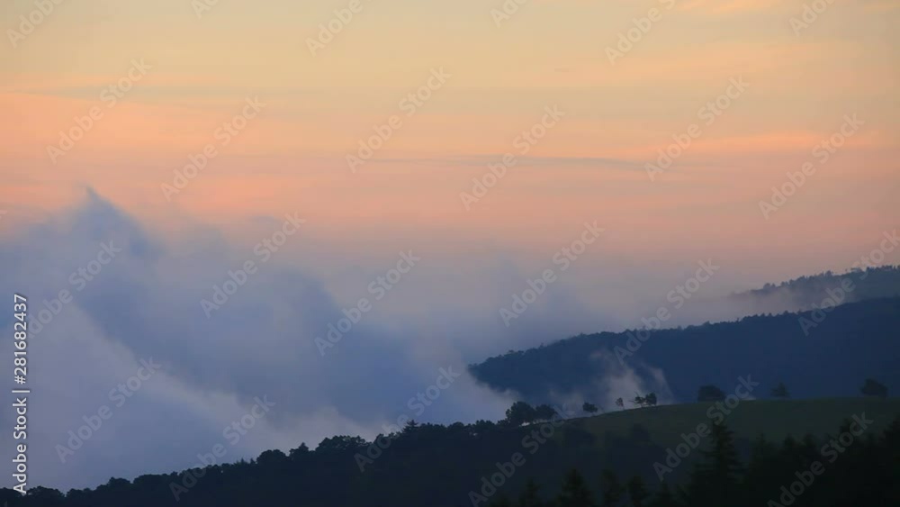 Clouds flowing over mountains at sunrise Clouds flowing over mountains at sunrise