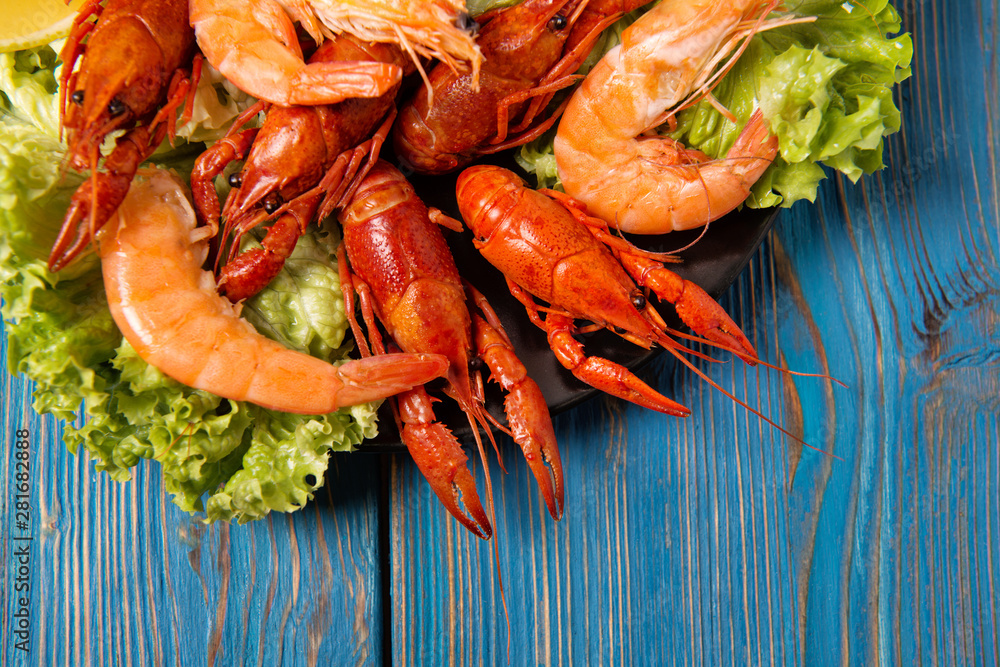 Boiled crayfish and shrimps with green salad and lemon slices on a plate, top view Boiled crayfish and shrimps with green salad and lemon slices on a plate, top view