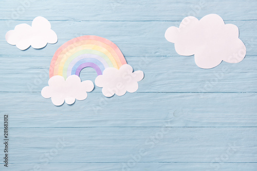 Children or baby background, white clouds with rainbow on the blue wooden background