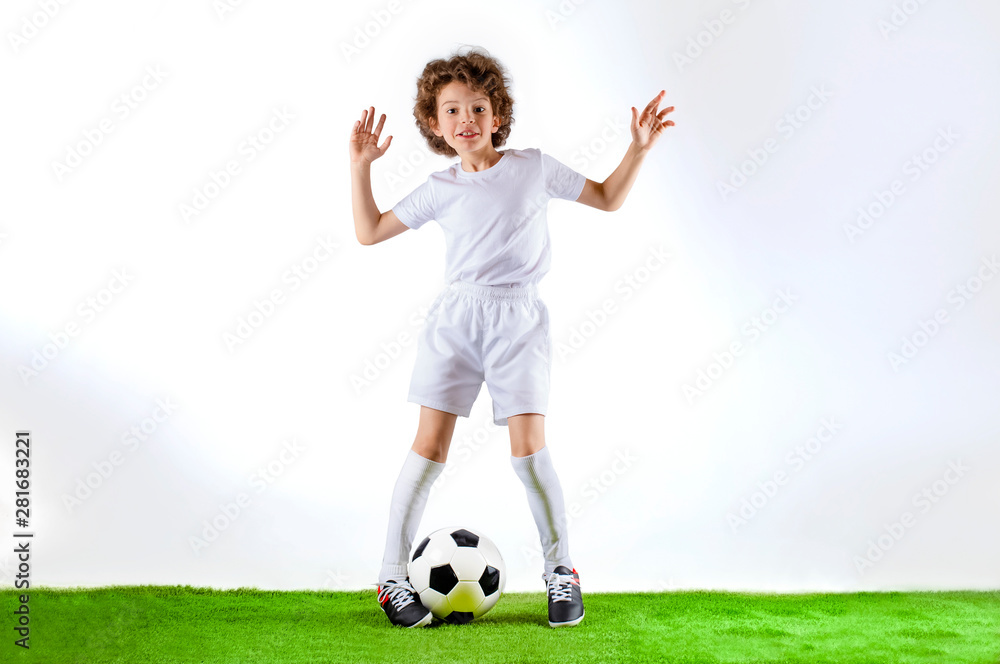 Boy with soccer ball on the green grass.Excited little toddler boy playing football on soccer field against light background. Active childhood and sports passion concept. Save space