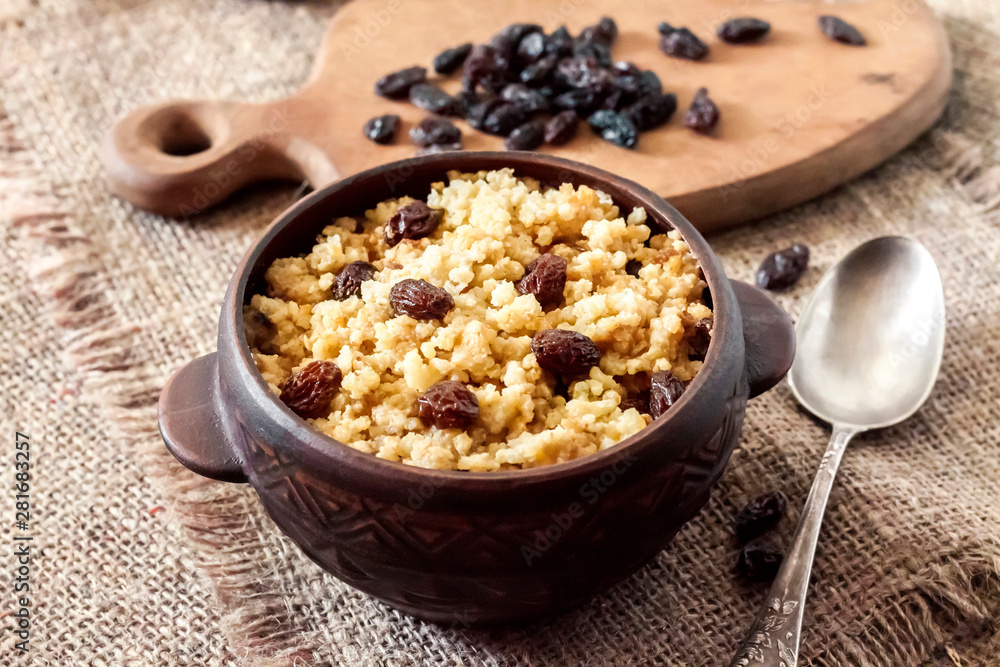 Sweet millet porridge with dark raisins in ceramic rustic bowl Sweet millet porridge with dark raisins in ceramic rustic bowl