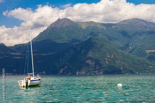 View to sailboat anchored in harbor the village of Varenna on Lake Como. Scenic landscape on background alps mountains  trees and water. Milan Province of Lecco. Italian region Lombardy  Italy Europe