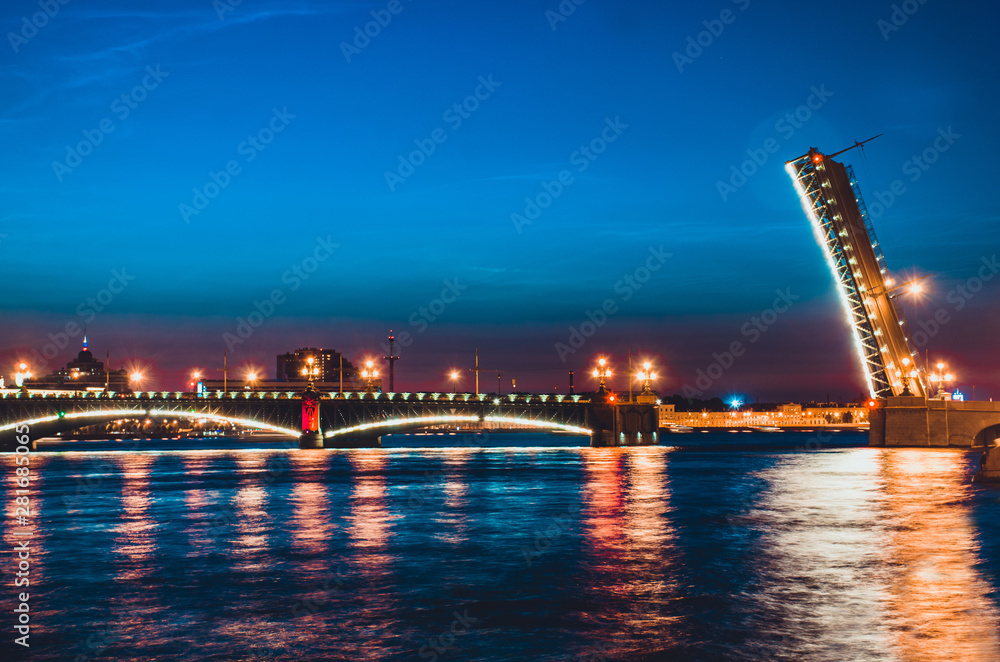 A famous illuminated drawbridge in Saint Petersburg at night with lights reflected in water. Trinity or Troitskiy bridge. Travelling to Russia well-known sight. Beautiful night river view.