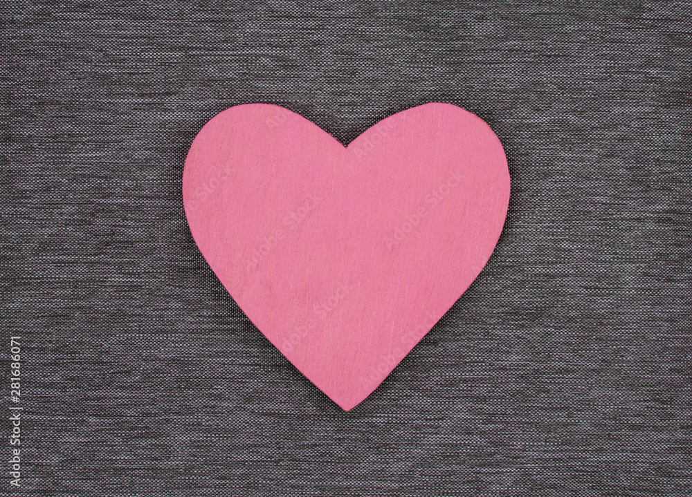 Wooden heart shape, on gray material, as a background texture with design space. Wooden heart shape, on gray material, as a background texture with design space.
