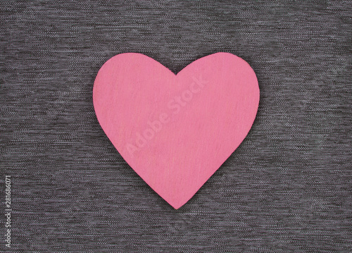Wooden heart shape, on gray material, as a background texture with design space.