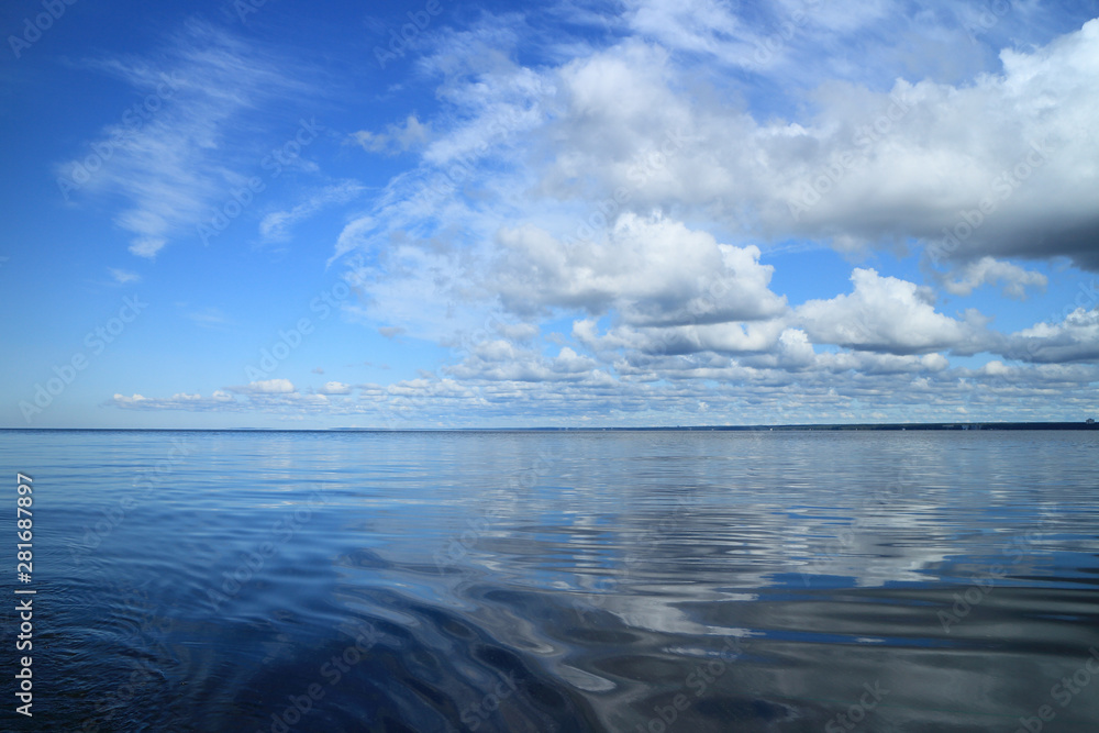 beautiful seascape cumulus clouds reflected in blue water, panorama