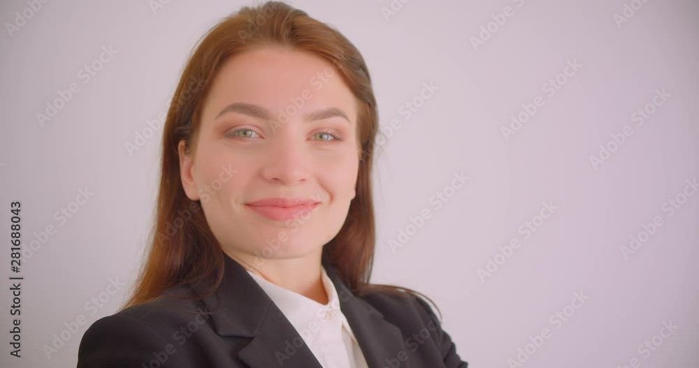 Closeup portrait of young caucasian businesswoman looking at camera smiling cheerfully with her arms crossed over chest in the white office Closeup portrait of young caucasian businesswoman looking at camera smiling cheerfully with her arms crossed over chest in the white office