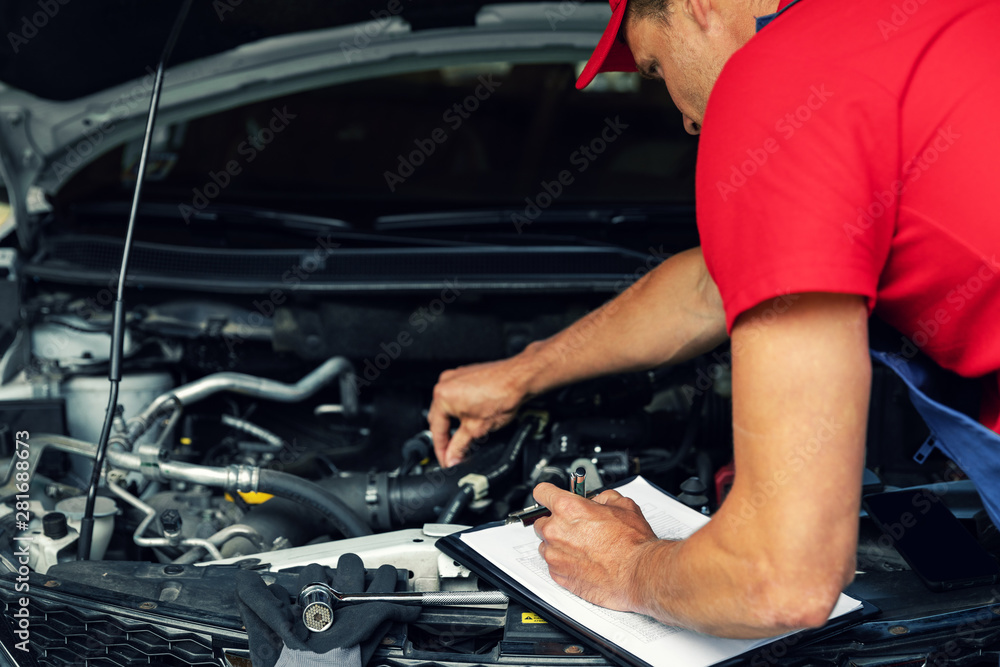 car maintenance - mechanic check the engine and writing in checklist car maintenance - mechanic check the engine and writing in checklist
