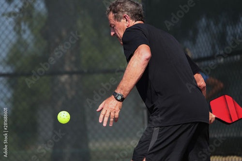 A senior athlete hits a shot, competing in singles, of a pickleball tournament. © Ron Alvey