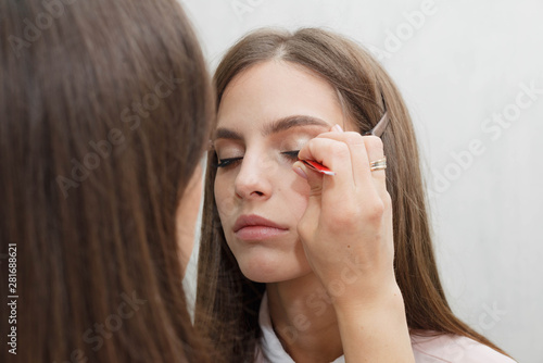 Makeup artist glues bunches on the eyelashes model.
