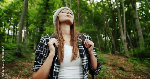 Attractive female tourist standing in forest and enjoying fresh mountain air, wilderness
