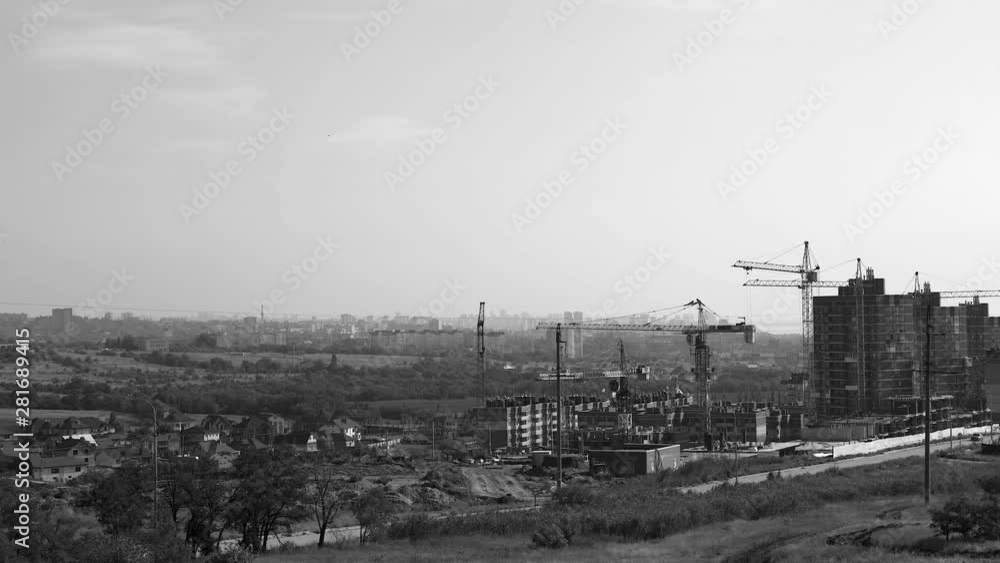 Several tower cranes build a multi-storey building and move cargo, long-range plan, time-lapse, monochrome Several tower cranes build a multi-storey building and move cargo, long-range plan, time-lapse, monochrome