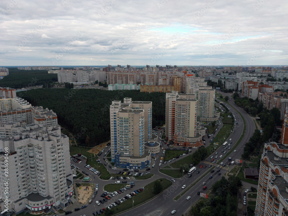 Fototapeta premium Aerial view of growing city on cloudy days. Drone view of new building complex in city center with houses and roads under cloudy sky