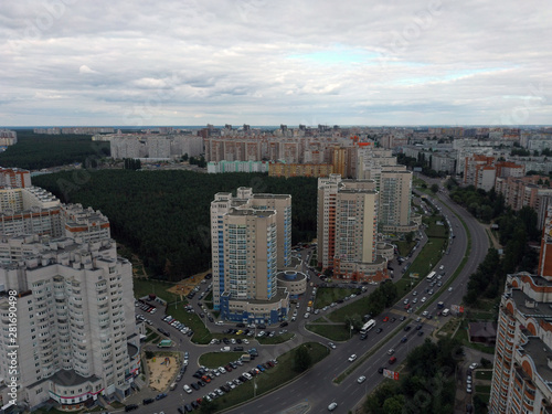 Aerial view of growing city on cloudy days. Drone view of new building complex in city center with houses and roads under cloudy sky