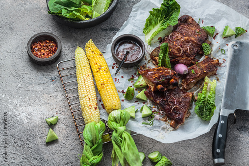 Pork ribs and corn on concrete background, copy space