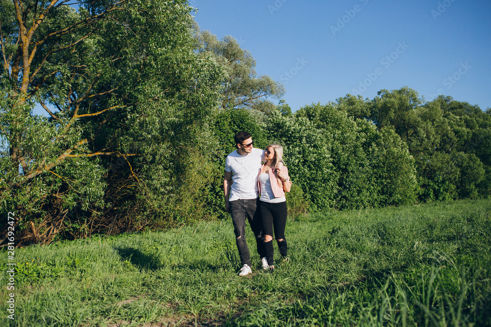 Young couple guy and girl walking arm in arm on the road