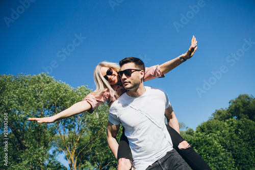 Girl sitting on the back of a man hugging and smiling in nature in summer