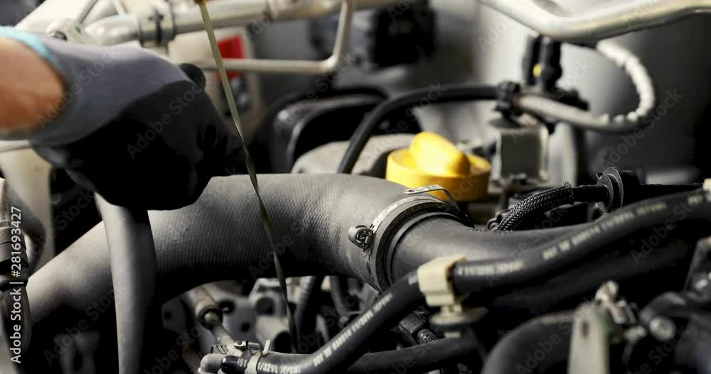 mechanic in garage doing car engine oil change and level inspection mechanic in garage doing car engine oil change and level inspection