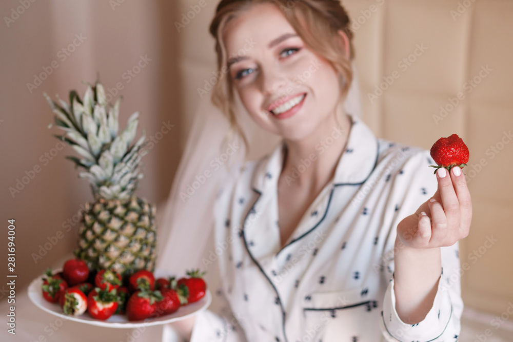 Young woman having breakfast in bed and eating strawberries Young woman having breakfast in bed and eating strawberries