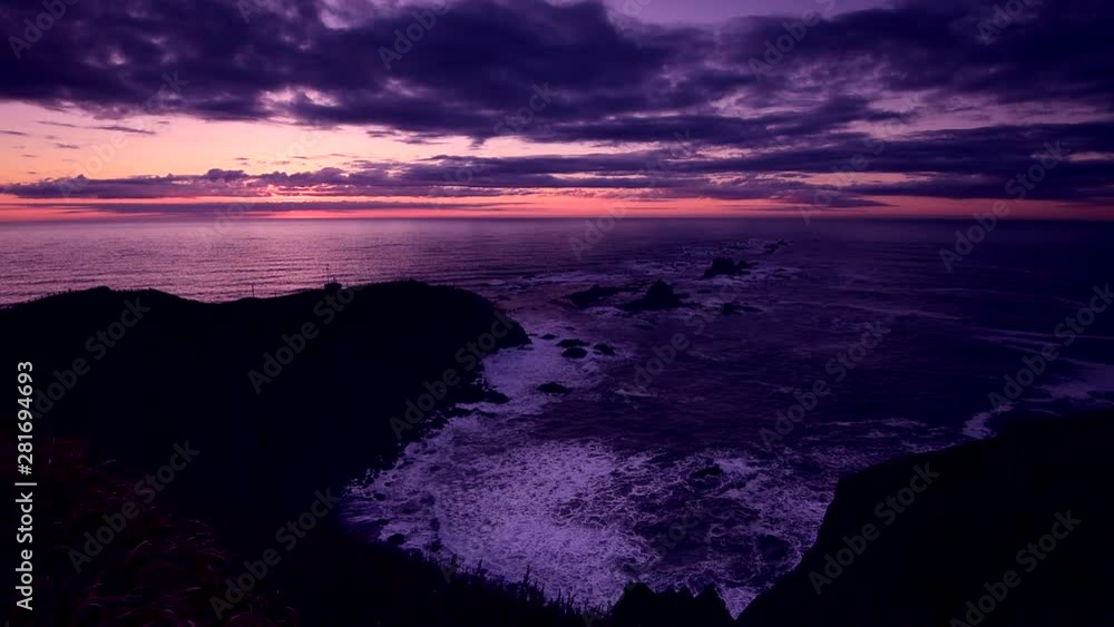 Clouds over rocky sea coast at purple dawn