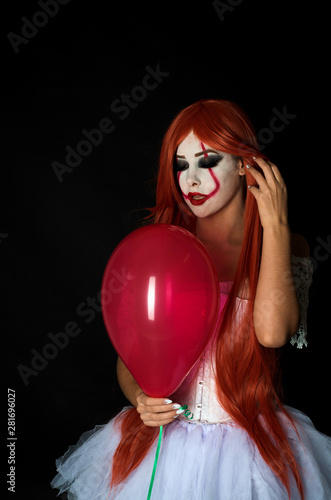 girl with red hair in clown costume on black background © евгений ставников