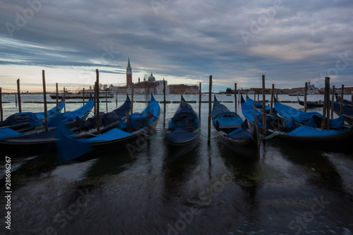 Gondolas in Venice at dusk taken on the shoreline besides the Piazza San Marco   St Marks Square.The image was taken during a dramatic sunset.