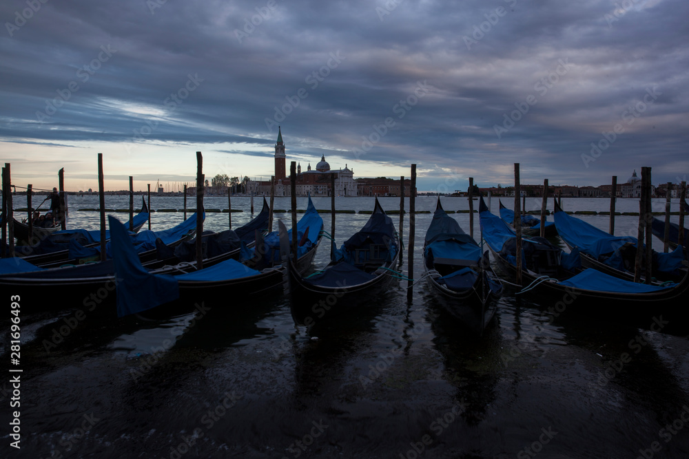 Gondolas in Venice at dusk taken on the shoreline besides the Piazza San Marco / St Marks Square.The image was taken during a dramatic sunset.