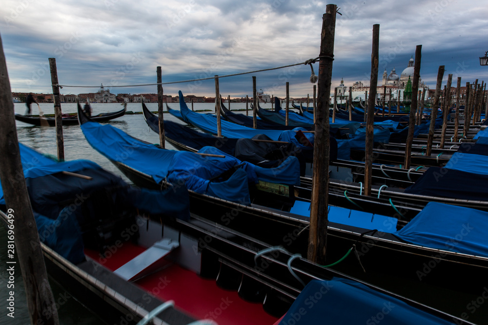 Gondolas in Venice at dusk taken on the shoreline besides the Piazza San Marco / St Marks Square.The image was taken during a dramatic sunset.