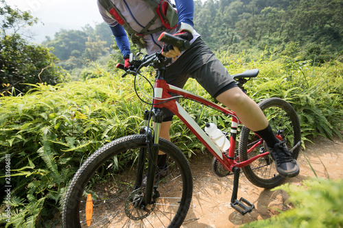Cross country biking woman cyclist with mountain bike on tropical rainforest trail