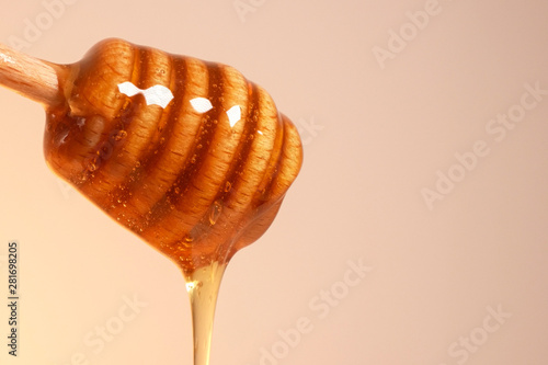 Fresh golden honey dripping from wooden honey dipper