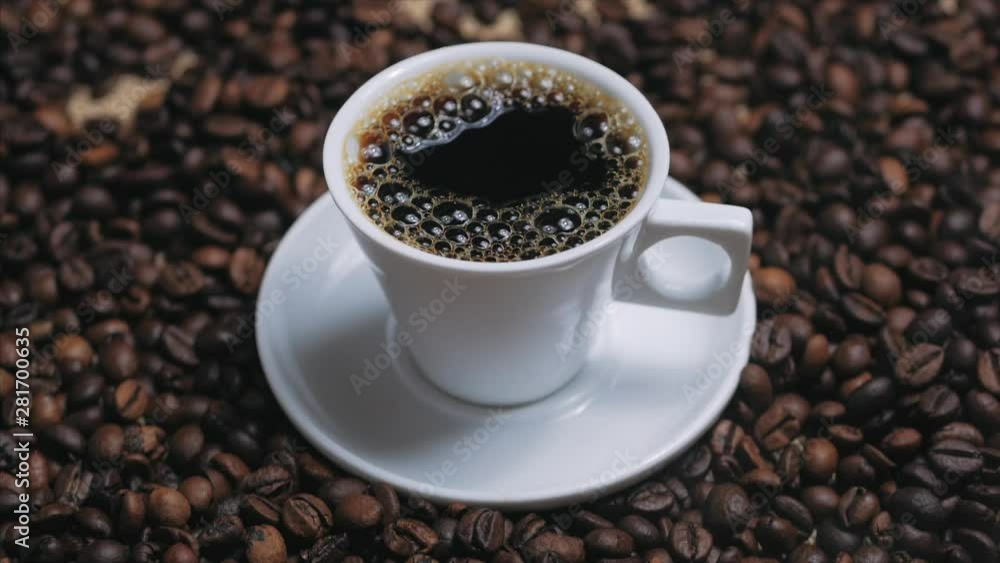 Coffee cup and coffee beans. White cup of evaporating coffee on the table with roasted bean. Stock footage. Coffee cup and coffee beans. White cup of evaporating coffee on the table with roasted bean. Stock footage.