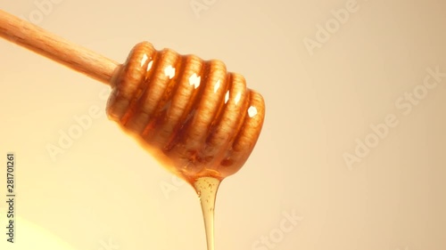 Golden natural honey dripping from wooden honey dipper