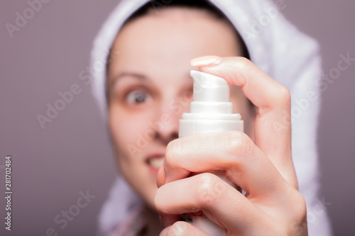 beautiful girl in a towel on the head in hand holding a cream