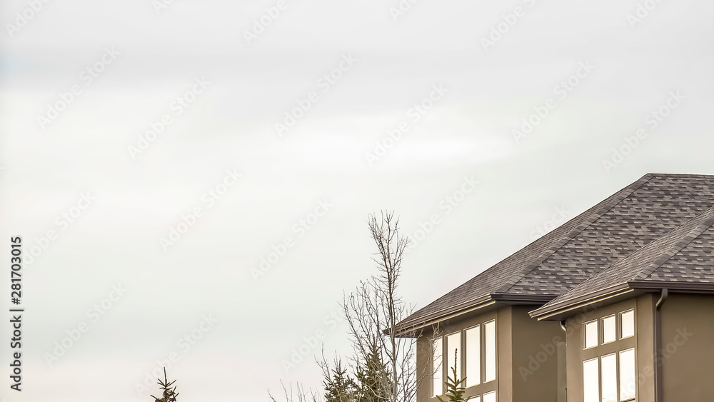 Panorama Exterior of home with stone brick and concrete wall against bright cloudy sky Panorama Exterior of home with stone brick and concrete wall against bright cloudy sky