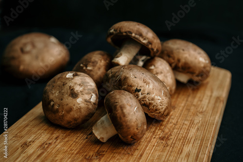 Champignons mushrooms on wooden board on black background